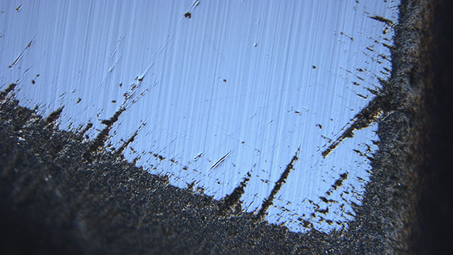 Figure 2. Differential interference contrast image near an apex of the stone showing the roughening of junctions between the faces and evidence of polishing after the roughening occurred. Image by David Fisher; field of view 0.48 mm.