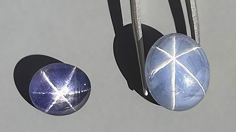 Figure 3. Exceptional star sapphires from Nivithigala, Sri Lanka, viewed in sunlight: a 7.45 ct purple color-change star sapphire (left) and a 19.74 ct light grayish blue star sapphire exhibiting an extraordinarily sharp and distinct star (right). Photo by Jennifer Stone-Sundberg; courtesy of Dudley Blauwet Gems. Figure 3. Exceptional star sapphires from Nivithigala, Sri Lanka, viewed in sunlight: a 7.45 ct purple color-change star sapphire (left) and a 19.74 ct light grayish blue star sapphire exhibiting an extraordinarily sharp and distinct star (right). Photo by Jennifer Stone-Sundberg; courtesy of Dudley Blauwet Gems.