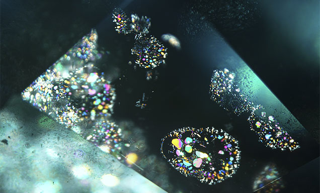 Iridescent thin films in aquamarine viewed with fiber-optic illumination. Photomicrograph by Michaela Damba; field of view 7.19 mm. Iridescent thin films in aquamarine viewed with fiber-optic illumination. Photomicrograph by Michaela Damba; field of view 7.19 mm.