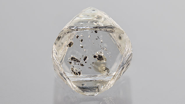 Figure 1. Weighing 1.17 ct and measuring 6.61 mm in the largest dimension, this partially etched colorless diamond octahedron hosts numerous opaque black chromite crystals. Photo by Rhonda Wilson. Figure 1. Weighing 1.17 ct and measuring 6.61 mm in the largest dimension, this partially etched colorless diamond octahedron hosts numerous opaque black chromite crystals. Photo by Rhonda Wilson.