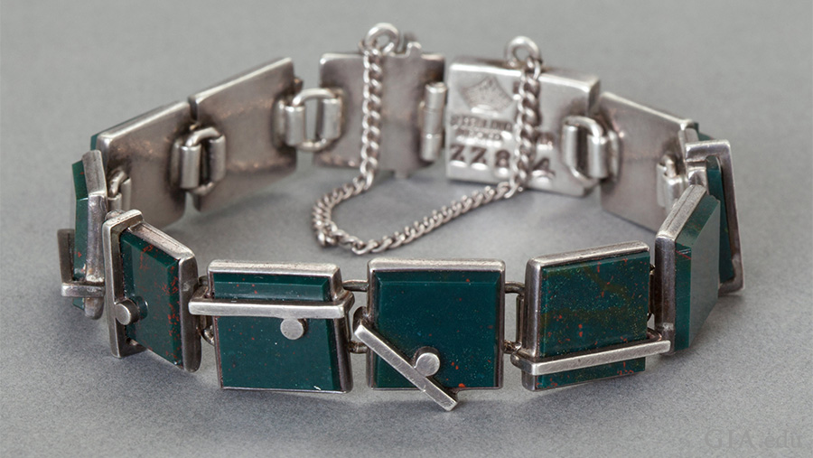 A rare Mexican silver bracelet featuring the March birthstone has bezel set bloodstones in silver, bar and ball overlay links, and is secured with a box clasp and chain. 