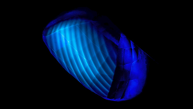 The curved banding in this flame-fusion synthetic blue sapphire is revealed by deep-UV illumination. 