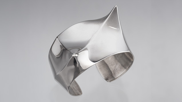Figure 2. One of two identical silver hollow-form bracelets by Frank Patania Jr. This cuff, known as both “Asymmetry” and “Twin Peaks,” was made around 1960 from six pieces of sterling silver using a small superstructure for support during the soldering process. The cuff weighs 100 g and measures 7 cm (2.75 in.) at its widest point. Photo by Robert Weldon; courtesy of Patania Jewelry. Figure 2. One of two identical silver hollow-form bracelets by Frank Patania Jr. This cuff, known as both “Asymmetry” and “Twin Peaks,” was made around 1960 from six pieces of sterling silver using a small superstructure for support during the soldering process. The cuff weighs 100 g and measures 7 cm (2.75 in.) at its widest point. Photo by Robert Weldon; courtesy of Patania Jewelry.