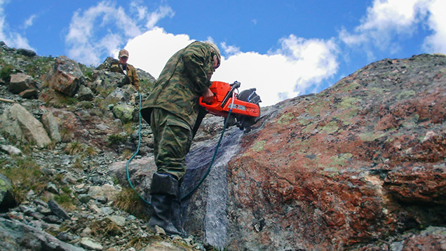 Miner sawing a rock to check its potential quality