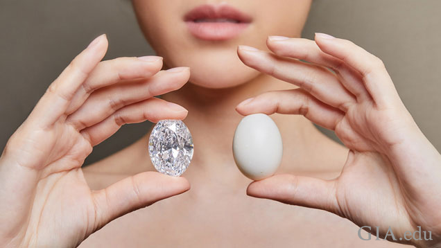 A model holds the diamond in one hand and a pigeon egg in the other.