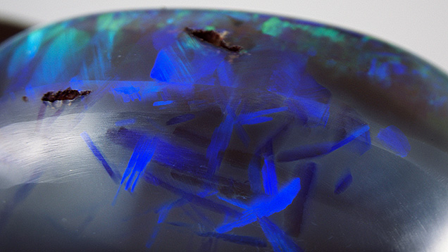Figure 1. A pattern resembling Chinese characters in an 8.13 ct black opal. Note that blade-like play-of-color patches exist within common opal. Photomicrograph by Makoto Miura; field of view 12.06 mm. Figure 1. A pattern resembling Chinese characters in an 8.13 ct black opal. Note that blade-like play-of-color patches exist within common opal. Photomicrograph by Makoto Miura; field of view 12.06 mm.