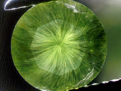 Horsetail inclusions are seen under the table of this faceted demantoid garnet. Horsetail inclusions are seen under the table of this faceted demantoid garnet.