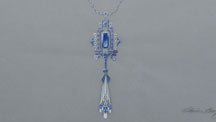 Jewelry design by Catherine Zheng of an Art Deco-inspired necklace featuring blue sapphire, tanzanite, diamonds and enamel. An ornate pendant hangs from a chain with stations of embellished links in between the chain. Photo by Emily Lane/GIA. 