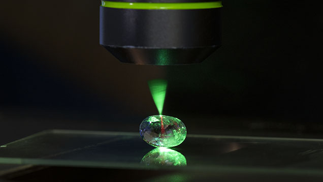 Figure 1. Microscope-assisted photoluminescence spectroscopy is an important technique for collecting data in gemological research and identification. Here, a 514 nm laser illuminates a sapphire sample at room temperature, creating red luminescence caused by trace amounts of chromium. Photo by Kevin Schumacher. Figure 1. Microscope-assisted photoluminescence spectroscopy is an important technique for collecting data in gemological research and identification. Here, a 514 nm laser illuminates a sapphire sample at room temperature, creating red luminescence caused by trace amounts of chromium. Photo by Kevin Schumacher.