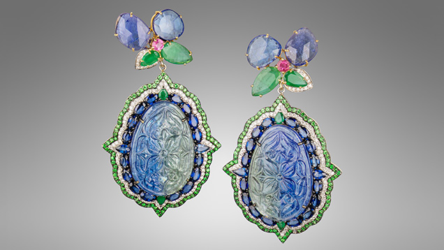 Figure 1. Surbhi’s “Orient” earrings with tanzanite carvings surrounded by blue sapphires, emeralds, white diamonds, and tsavorite garnets with an upper flower-shaped dangle composed of faceted tanzanites, emeralds, and pink sapphires, all set in 18K white gold. The total diamond weight for the pair is 1.60 carats, and the total colored stone weight is 62.23 carats, 48.32 carats of which are from the two tanzanite carvings. Photo by Robert Weldon; courtesy of YNY Jewels Inc. and Karats Inc. Figure 1. Surbhi’s “Orient” earrings with tanzanite carvings surrounded by blue sapphires, emeralds, white diamonds, and tsavorite garnets with an upper flower-shaped dangle composed of faceted tanzanites, emeralds, and pink sapphires, all set in 18K white gold. The total diamond weight for the pair is 1.60 carats, and the total colored stone weight is 62.23 carats, 48.32 carats of which are from the two tanzanite carvings. Photo by Robert Weldon; courtesy of YNY Jewels Inc. and Karats Inc.