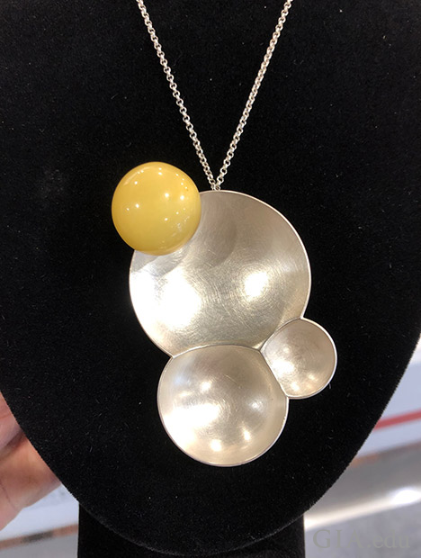 A ball of Baltic amber sits on a three-ring composition of textured silver.