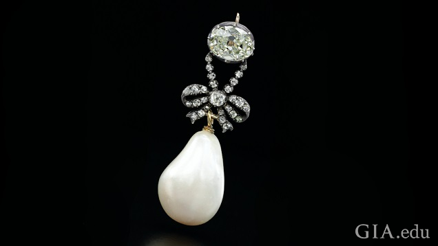 A large pear shaped diamond sits on a silver plaque with French words. A large pear shaped diamond sits on a silver plaque with French words.