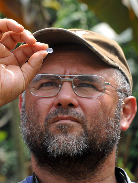 Close up shot of Manuel Diaz as he holds a blue spinel up in front of his eyes.