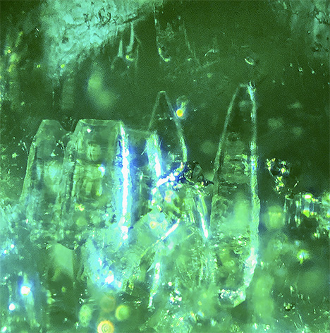 Colorless transparent parisite crystals in emerald. Colorless transparent parisite crystals in emerald.