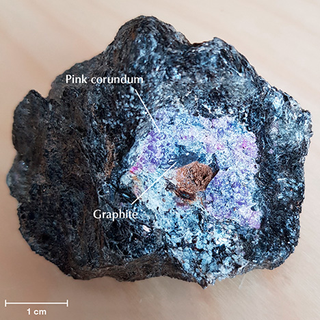 Pink corundum with a graphite inclusion. Pink corundum with a graphite inclusion.
