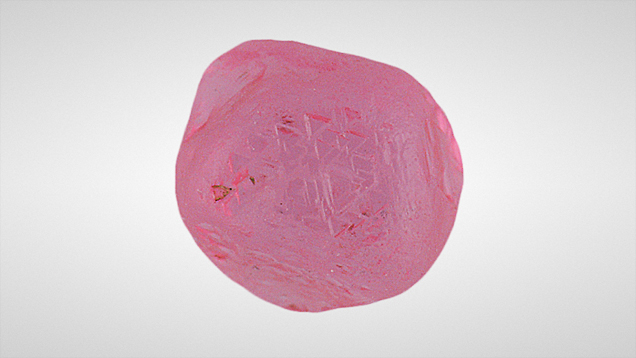 This rough spinel, submitted as a diamond, displayed trigons oriented in the direction opposite that of the crystal face.