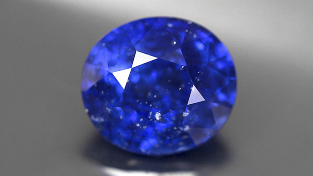 Oval blue sapphire displays eye-visible white inclusions. Oval blue sapphire displays eye-visible white inclusions.