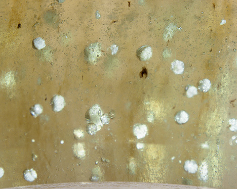 Figure 3. White spherulites in the bangle were identified as cristobalite by Raman analysis. Photomicrograph by Sze Ling Wong; field of view 5.98 mm. Figure 3. White spherulites in the bangle were identified as cristobalite by Raman analysis. Photomicrograph by Sze Ling Wong; field of view 5.98 mm.