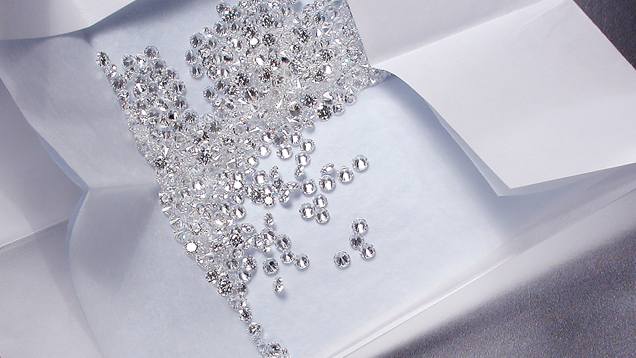 Round brilliant cut diamonds spilling out of a partially unfolded stone paper. Round brilliant cut diamonds spilling out of a partially unfolded stone paper.