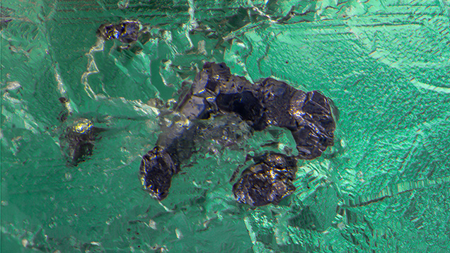 Figure 2. A combination of optical microscopy and Raman analysis identified the opaque silvery gray monoclinic inclusions as the very rare sulfide geocronite. Photomicrograph by Nathan Renfro; field of view 2.39 mm. Figure 2. A combination of optical microscopy and Raman analysis identified the opaque silvery gray monoclinic inclusions as the very rare sulfide geocronite. Photomicrograph by Nathan Renfro; field of view 2.39 mm.