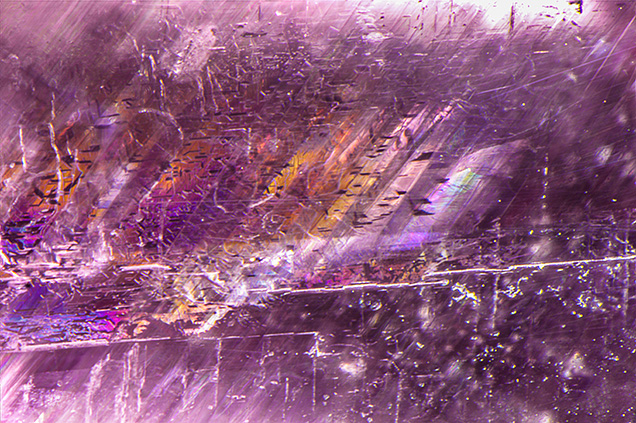 Figure 2. Twinning planes and fluid fingerprints were observed throughout the faceted purple anhydrite. Photomicrograph by Nathan Renfro; field of view 3.89 mm.