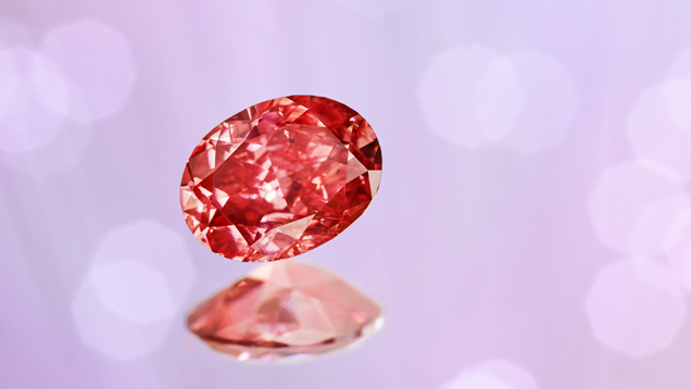 A oval shape red diamond on a pink, blue, purple and white background. A oval shape red diamond on a pink, blue, purple and white background.