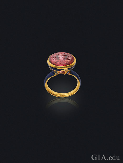 A carved spinel sits on the top of an enamel seal ring. A carved spinel sits on the top of an enamel seal ring.