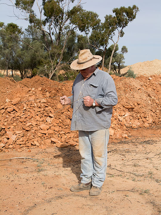 DSC_3249-540x720.jpg. Raleigh Henderson uses divining rods to search for signs of boulder opal at his mine in the Yowah area. Photo by Andrew Lucas/GIA.