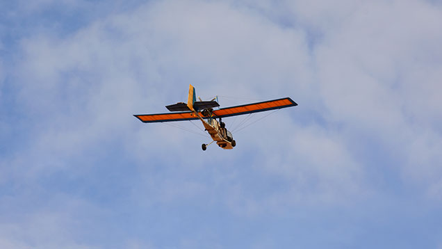 Ultralight plane in sky. 砾岩蛋白石矿工 Colin Stelzer（科林·施特尔策）对于超轻型飞机的激情象征着澳大利亚蛋白石矿工的独立、自由精神和对冒险的激情。 摄影：Andrew Lucas（安德鲁·卢卡斯）/GIA。