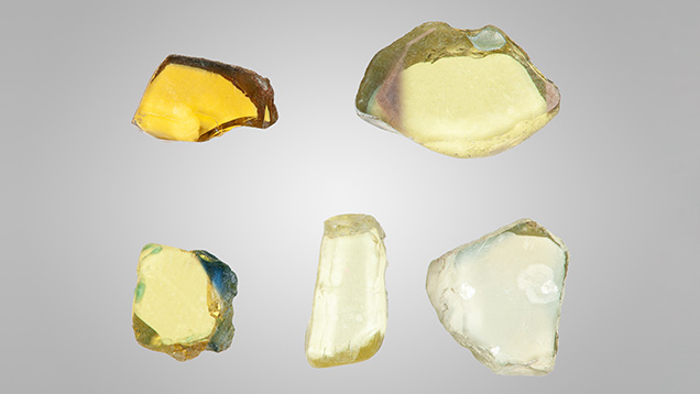 Figure 2. A selection of the 102 wafers studied for this report. The three pale yellow wafers are colored by Fe3+ only at a level around 2000 ppma, while the more color-saturated wafer with a blue edge is colored by a much higher concentration of Fe3+ (around 3500 ppma). The deep yellow wafer is colored by Fe3+ and by h•-Fe3+. Photo by John L. Emmett.
