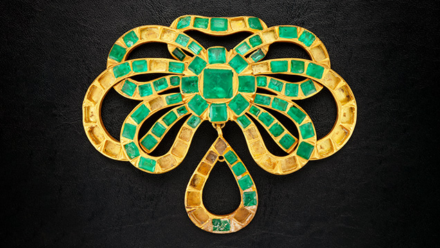 Figure 2. This gold and emerald pendant contains 61 Colombian emeralds with 33 stones missing, presumably lost during its residence on the seafloor for more than 300 years. The pendant is approximately 3.5 in. (8.9 cm) wide. Photo by Emily Lane. Figure 2. This gold and emerald pendant contains 61 Colombian emeralds with 33 stones missing, presumably lost during its residence on the seafloor for more than 300 years. The pendant is approximately 3.5 in. (8.9 cm) wide. Photo by Emily Lane.