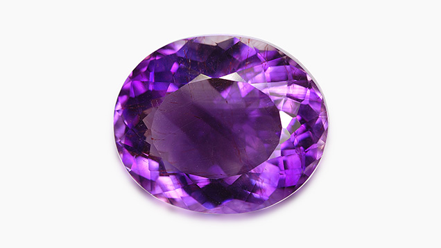 Faceted amethyst displaying red hematite needles Faceted amethyst displaying red hematite needles
