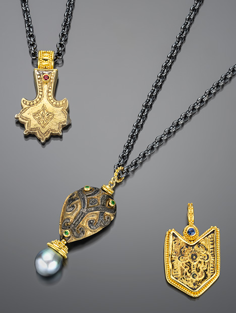 Three ornate necklaces featuring intricate pendants: one with a gold design, another with a patterned stone, and a third with a blue gem. Three ornate necklaces featuring intricate pendants: one with a gold design, another with a patterned stone, and a third with a blue gem.