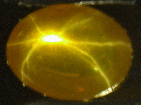 Yellow-orange synthetic sapphire showing star in transmitted light Yellow-orange synthetic sapphire showing star in transmitted light