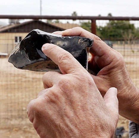 Figure 3. Dodge describes taking a chip off of the rough. This provides a “window” into the stone so he can spot flow bands in the glass. The flow bands give rise to the phenomenal colors, and provide guidance in his lapidary work. Photo by Pedro Padua. Figure 3. Dodge describes taking a chip off of the rough. This provides a “window” into the stone so he can spot flow bands in the glass. The flow bands give rise to the phenomenal colors, and provide guidance in his lapidary work. Photo by Pedro Padua.