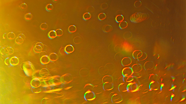 A 6.28 ct faceted yellow sphene exhibited interference “soap bubbles.” Photomicrograph by Ungkhana Atikarnsakul; field of view 3.6 mm.
