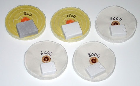 「800」と「1500」と表示された2つの加工済みイエローホイールと、「4000」、「6000」、「8000」と表示された3つの白いホイールは、バフに塗布されたプラチナ用研磨剤の研磨グレードを表している。