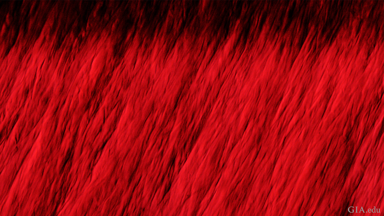 Chevron-shaped graining is diagnostic of the hydrothermal growth method used to produce this Tairus synthetic ruby. Field of view 1.22 mm. Photomicrograph by GIA staff. Chevron-shaped graining is diagnostic of the hydrothermal growth method used to produce this Tairus synthetic ruby. Field of view 1.22 mm. Photomicrograph by GIA staff.