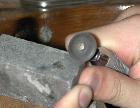 Close-up view of a jeweler using a shaping stone to shape an abrasive wheel