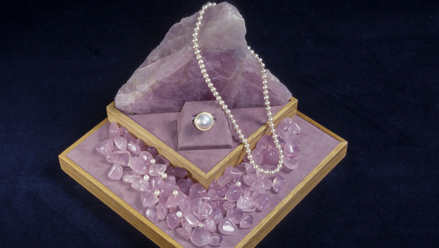 蔷薇石英珠子、凸圆面和原石非常紧凑地布置在商店的展示柜中，十分显眼。 – Robert Weldon（罗伯特·韦尔登）