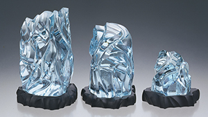 Three light-to-medium blue carved sculptures sit in a line – from larger to smaller.