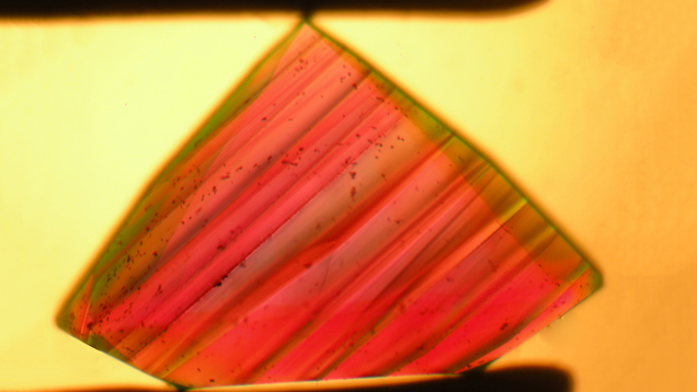 This microphotograph shows layered growth zoning associated with intense color zoning in a faceted synthetic alexandrite grown by Creative Crystals Inc.; immersion, field of view 5.3 × 4.0 mm. Photo courtesy of K. Schmetzer, The Journal of Gemmology.