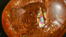 Reflection from a cleavage plane causes the iridescent colors in this oligoclase sunstone cabochon.