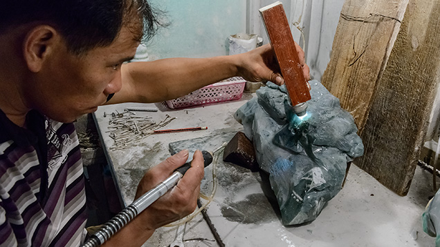 Artist in initial stages of carving rough jadeite