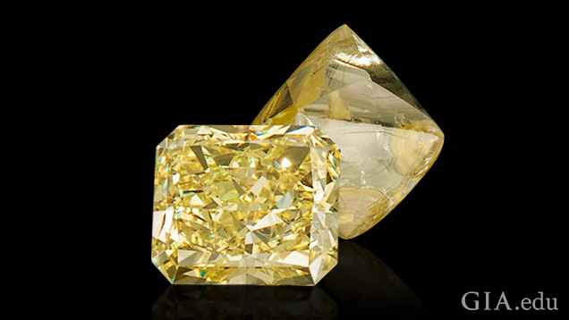 A polished and cut yellow diamond sits in front of a rough yellow diamond.