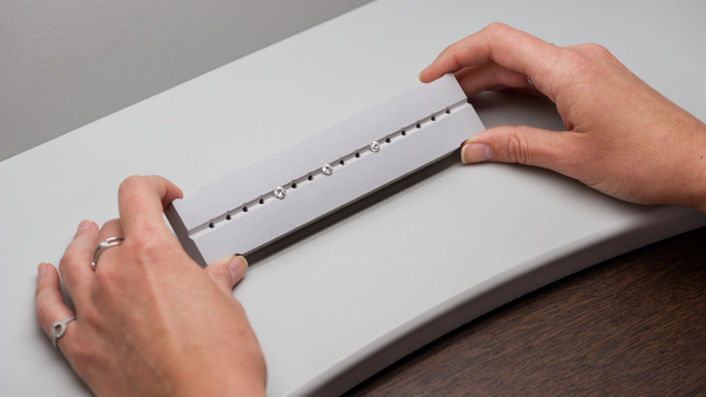 Close-up of hands holding a tray with three diamonds to observe in Diamond Dock. 