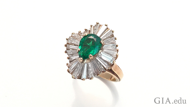 This emerald ring in a yellow gold mounting with tapered baguette diamonds is from the GIA Collection and was photographed with a mobile phone. It was photographed on a white tile background using museum wax to hold the ring up. Diffusion paper and reflector cards were used to light up the gems. Photo by Robert Weldon and Denise Conrad / GIA.