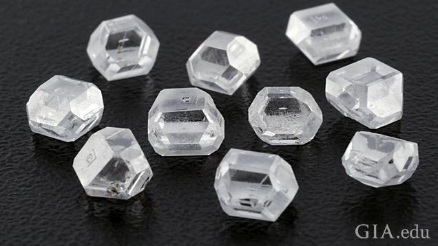 A group of 10 colorless rough crystals on a black background.