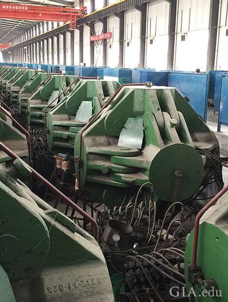 A row of HPHT synthetic diamond presses machinery in a large factory.