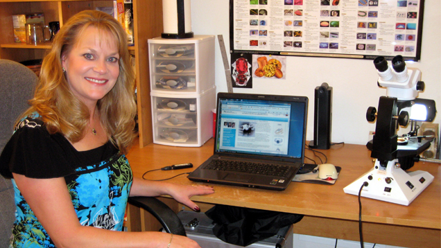 Michelle M. Rahm（米歇尔·M.拉姆）坐在电脑、显微镜和宝石图表前。